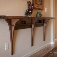 a wooden shelf sitting on top of a wall next to a framed painting and vases