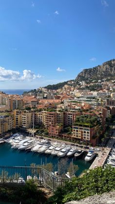 boats are docked in the water near some buildings and mountains with blue skies above them