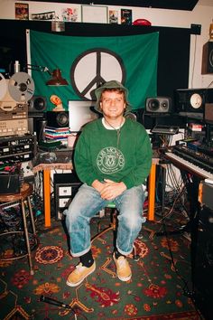 a man sitting in front of a green peace sign