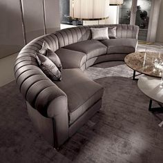 a large sectional couch sitting in the middle of a living room next to a round table