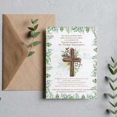 a wedding card with a cross and greenery on it next to a brown envelope