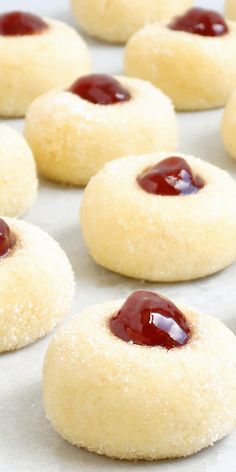 small cookies with jam on them sitting on a baking sheet, ready to be baked