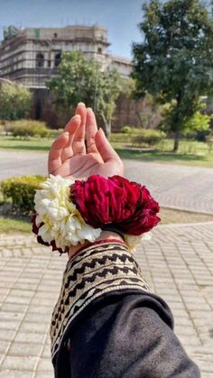 a person with their hand in the air holding flowers