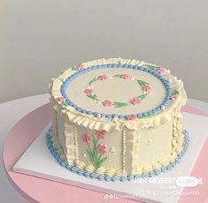 a decorated cake sitting on top of a pink and white tablecloth covered plate with flowers