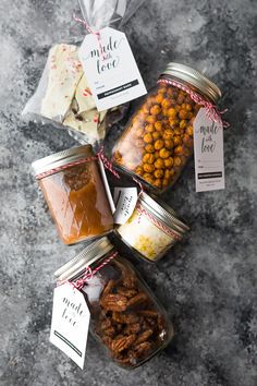 four jars filled with different types of candies and nuts on top of a table