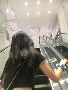 a woman is riding down an escalator with her hand on the railing while wearing gloves