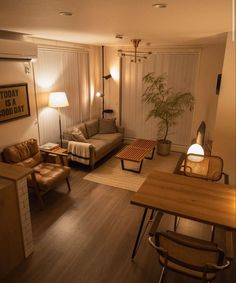 a living room filled with furniture next to a wooden table and lamp on top of a hard wood floor