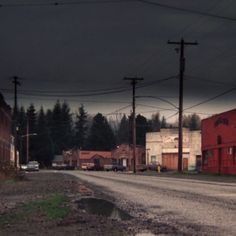 an empty street with power lines and buildings in the background on a gloomy day