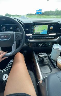 a person sitting in the driver's seat of a car with their feet on the steering wheel