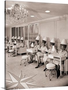 an old black and white photo of some women in uniforms sitting at desks with paper hats on their heads