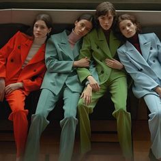 three models in colorful suits sitting on a bench