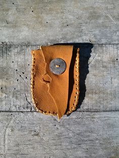 a piece of leather with a button in it sitting on top of a wooden surface