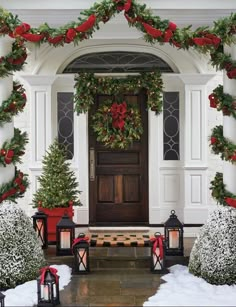 someone is holding up a christmas card in front of a house with wreaths on it