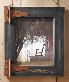 a painting hanging from the side of a wall next to a wooden frame with an old rocking chair on it