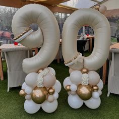 two large balloons that are shaped like the number 50 with gold and white balloons attached to them