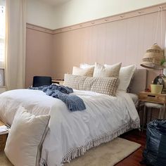 a bed with white linens and pillows in a bedroom next to a wooden table