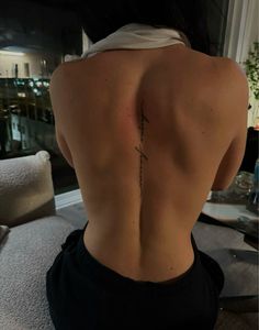 the back of a woman's body with a cross tattoo on her lower back