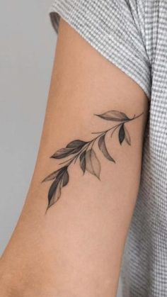 a woman's arm with a small branch tattoo on the left side of her arm