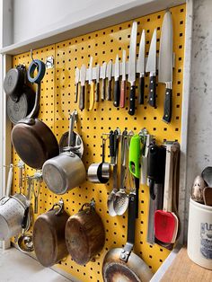 a peg board with lots of kitchen utensils hanging from it's side