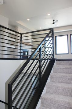 a stair case with black railing and white handrail next to carpeted flooring