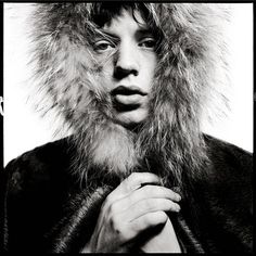 a black and white photo of a woman with fur on her head wearing a coat