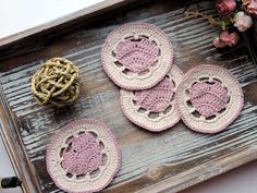 four crocheted coasters sitting on top of a wooden table