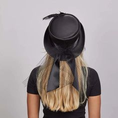 Step out in style with this gorgeous Victorian leather top hat. Crafted of luxurious leather and decorated with a satin black band, overlay mesh, bow closure, antique medallion and feathers, it provides an elegant yet edgy look. An undeniable head-turner, this hat adds flair to any ensemble. Featuring a super comfortable removable sweatband liner that attaches securely with velcro tabs sewn-in to the hat. Easily swap the liner for a half or full-size reducing sweatband (included with purchase) t Elegant Halloween Fascinator, Victorian Top Hat With Short Brim For Party, Elegant Fitted Top Hat For Halloween, Elegant Top Hat For Halloween Party, Evening Top Hat With Feathers And Short Brim, Elegant Adjustable Hat For Halloween, Elegant Top Hat For Halloween, Elegant Short Brim Halloween Hat, Elegant Black Mini Hat For Halloween