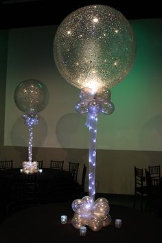 two large clear balloons sitting on top of a table next to candles and lights in front of a projection screen