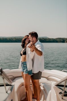 a man and woman standing on top of a boat in the water with their arms around each other