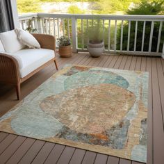 an area rug on a deck with a couch and chair next to it, in front of a balcony