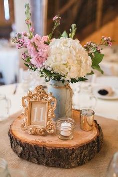 a vase filled with white and pink flowers on top of a wooden table next to a mirror