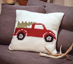 a red truck pillow sitting on top of a brown couch next to antler's antlers