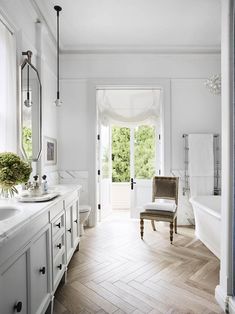 the bathroom is decorated in white and has an open door that leads to another room