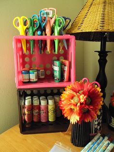 a desk with scissors, pens, markers and other crafting supplies on it next to a lamp