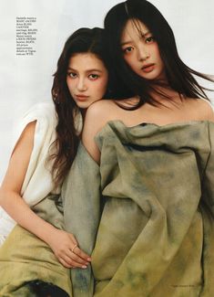 two young women sitting on top of each other wrapped up in blankets and posing for the camera