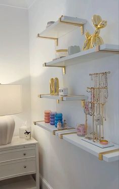 the shelves in this room are decorated with gold and white accessories, such as necklaces