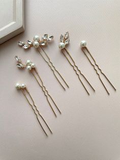 Indulge in elegance with our set of 5 exquisite bridal hair pins. Crafted from top-tier materials including crystal rhinestones, lustrous pearl beads, and silver-plated jewelry wire, these wedding hair pins are customizable with a range of rhinestone colors.  Discover the timeless elegance of our pearl hair pins, meticulously crafted to grace the hairstyles of brides, bridesmaids, and prom-goers alike. Radiating sophistication and grace, these pearl hair pins are the quintessential accessory for those seeking refined beauty on their special day. Their versatility effortlessly complements the bridal ensemble, adding a touch of glamour and charm. Whether adorning the bride's hair with understated grace or accentuating the bridesmaids' styles with elegance, these pins are a statement of endur Hair Accessories For Prom, Pearl Pins In Hair, Bridal Hair With Pearls, Wedding Hair Pearls, Pearl Wedding Accessories, Decorative Hair Pins, Pearl Wedding Hair, Hair Piece Wedding Hair, Wedding Bun