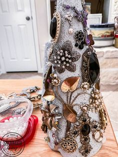 a close up of a tree made out of jewelry on a wooden table with a door in the background