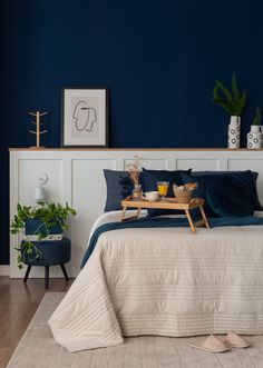 a bedroom with blue walls and white bedding has a tray on the headboard