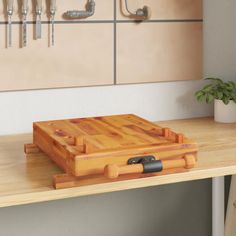 a wooden cutting board sitting on top of a table next to a potted plant