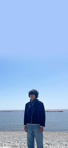 a man standing on top of a sandy beach next to the ocean