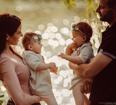 three adults and two children are standing by the water with their hands on each other's shoulders