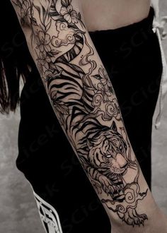 a woman's arm with a tiger and flowers tattoo on the left side of her body