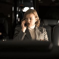 a woman talking on a cell phone while sitting in a bus with another person behind her