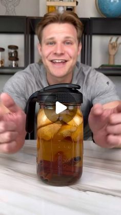 a man holding up a mason jar filled with pickles and lemons in it