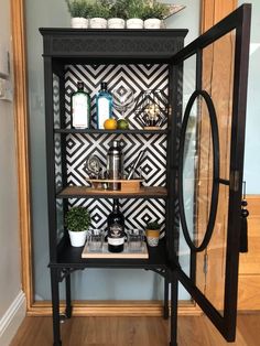 a black and white display case with plants on it's shelves in front of a door