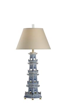 a blue and white table lamp with a beige shade on the top, in front of a white background