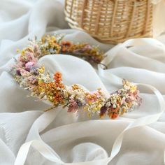 a flower crown laying on top of a white cloth next to a wicker basket