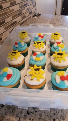 cupcakes decorated with smiley faces and sunglasses in a plastic container on a counter