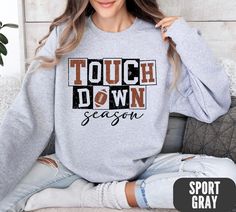 Football Season Touchdown Distressed Graphic Sweatshirt   Stay cozy and stylish this season with our trendy sweatshirt featuring a bold design! The word touchdown stands out in alternating color blocks, with the word season written neatly underneath in a distressed graphic. This unique and eye-catching sweatshirt is perfect for adding a sporty touch to your casual outfits. Made with high-quality materials, this sweatshirt is both comfortable and fashionable, making it a must-have for any wardrob Gray Sweatshirt For Game Day In Fall, Gray Slogan Sweatshirt For Fall, Relaxed Fit Sweatshirt For Game Day And Winter, Long Sleeve Text Print Sweatshirt For Sports Season, Winter Game Day Relaxed Fit Tops, Gray Graphic Print Sweatshirt For Game Day, Relaxed Fit Sweatshirt With Text Print For Game Day, Relaxed Fit Text Print Sweatshirt For Game Day, Relaxed Fit Sweater With Letter Print